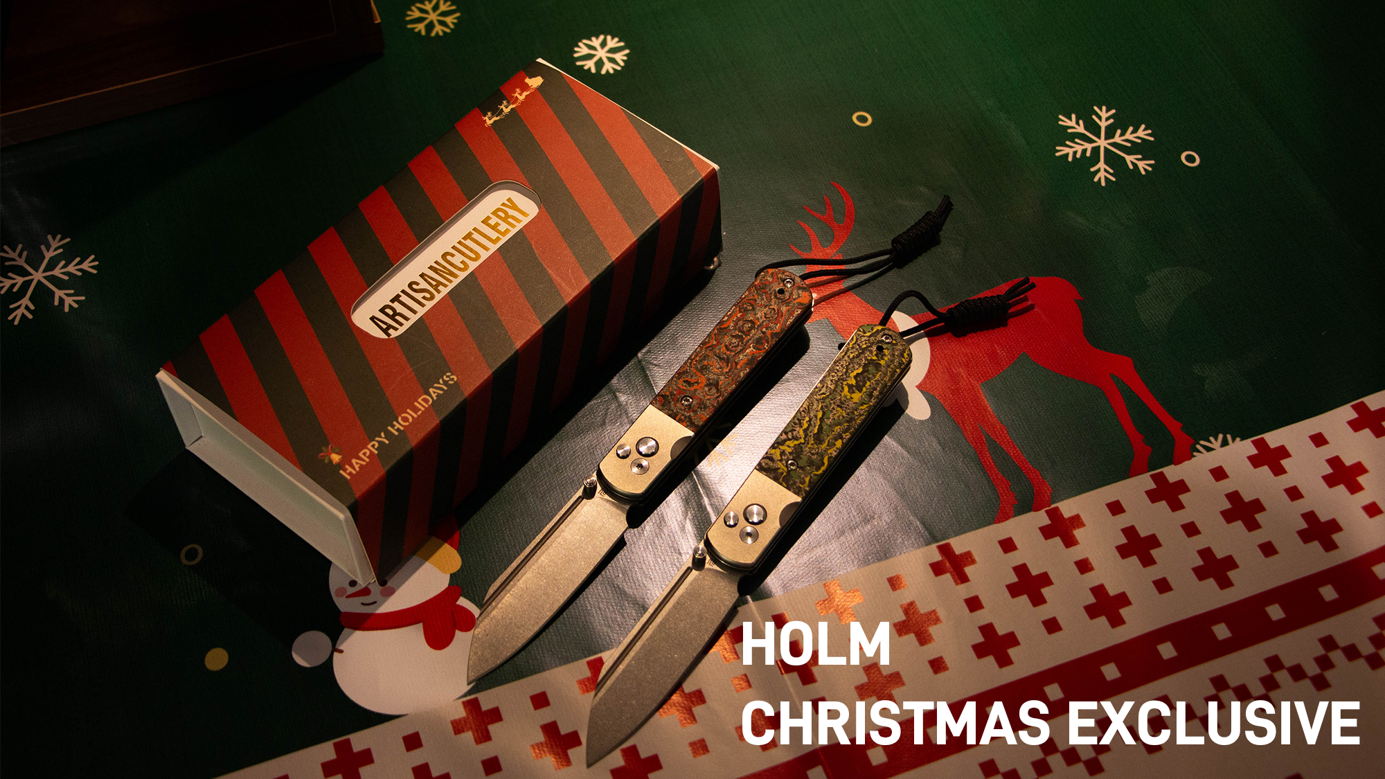 Two ornate folding knives next to a gift box on a festive green background with snowflakes and a reindeer.