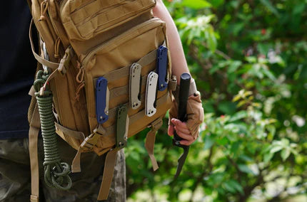 A person wearing a tactical backpack with various knives attached to it.