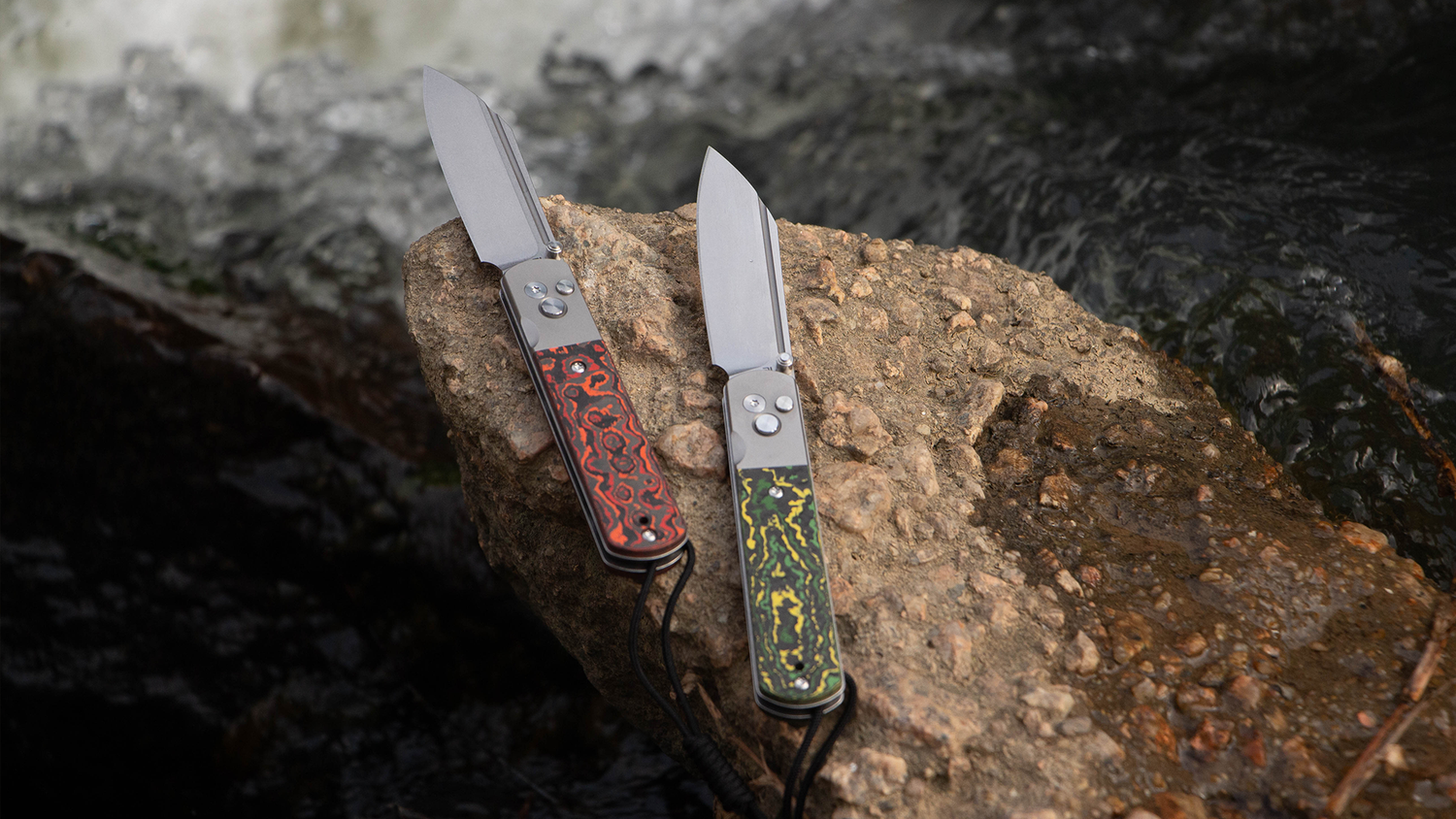 Two folding knives with decorative handles on a rock.